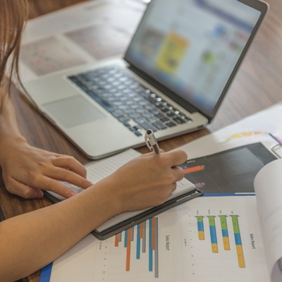 Persona usando una laptop, notebook y gráficos para trabajar.