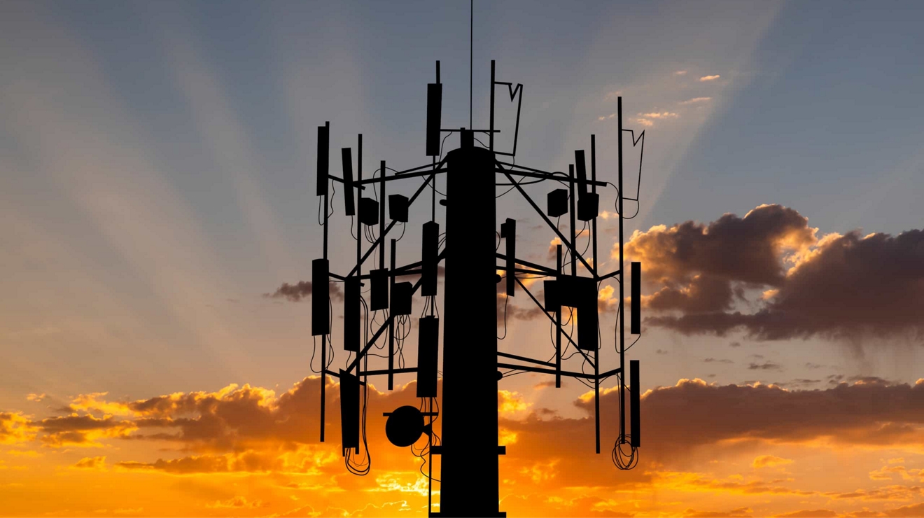 Una torre celular con el cielo del atardecer de fondo.