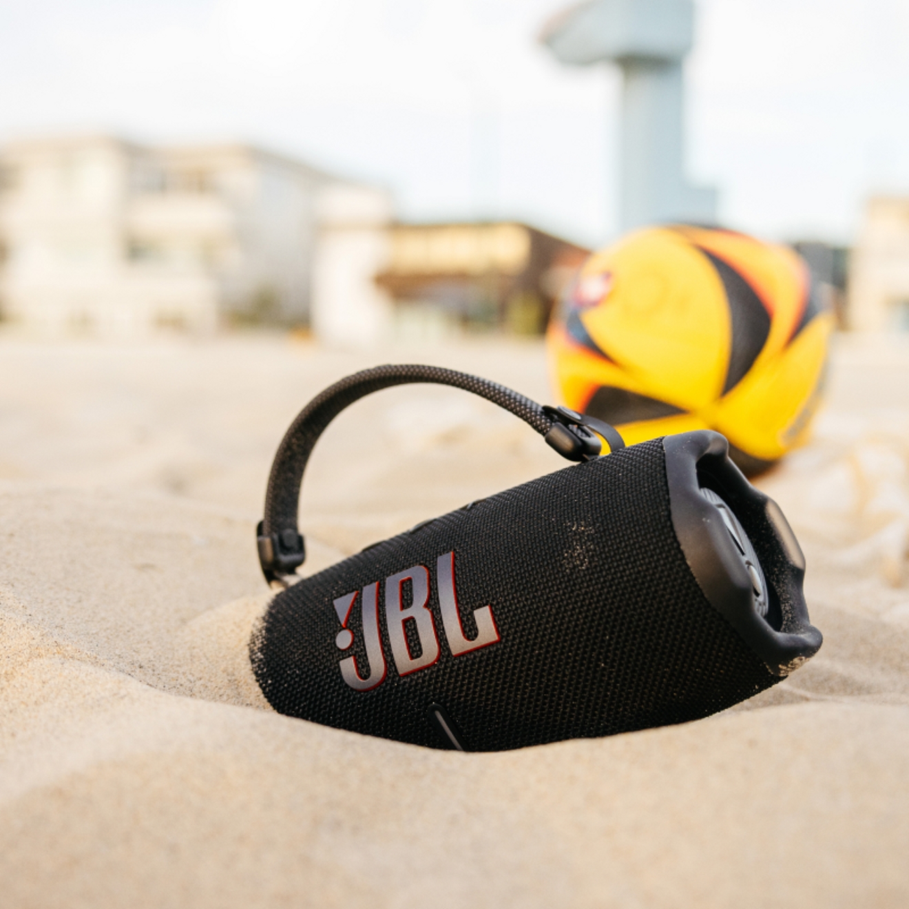 Un dispositivo JBL Charge en la arena de una playa