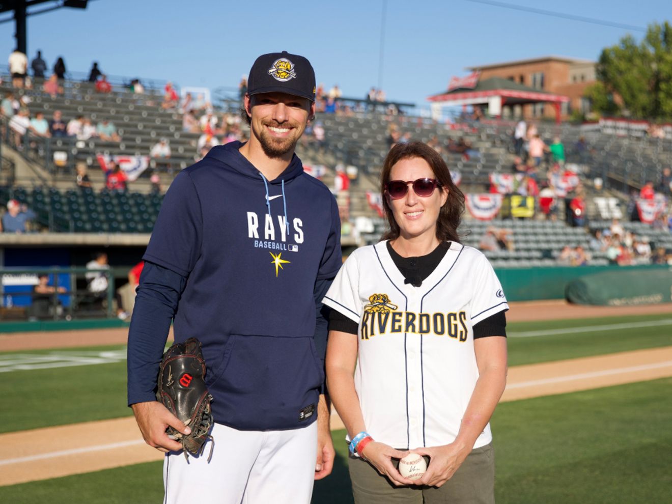 Julie Walker, veterana de la Fuerza Aérea de EE. UU., está de pie en un campo de béisbol junto a un jugador de béisbol.