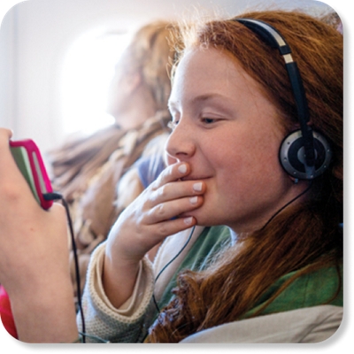 Durante un vuelo, una niña escucha con sus auriculares y mira su teléfono.
