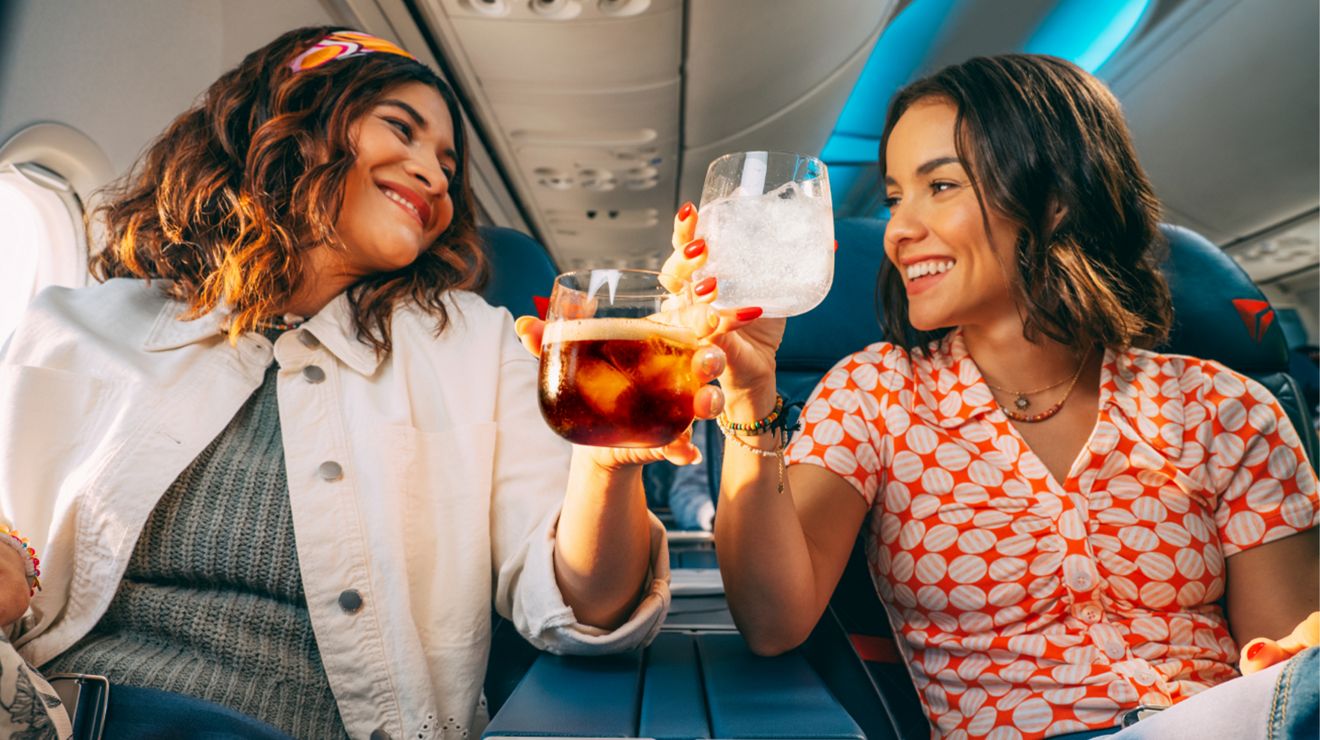 Dos pasajeros de Delta chocan sus bebidas para brindar.