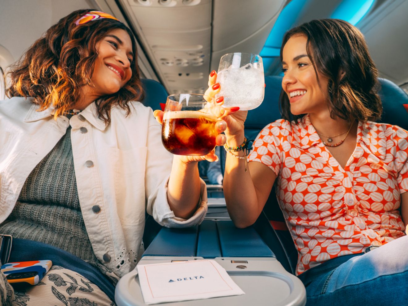 Dos pasajeros de Delta chocan sus bebidas para brindar.