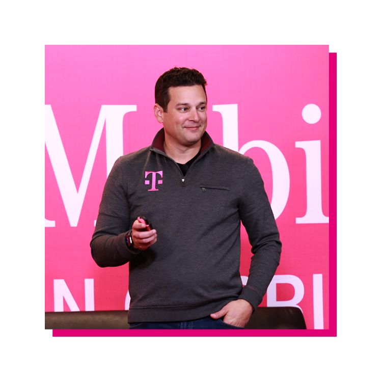Mike Katz parado enfrente de un banner magenta de T-Mobile
