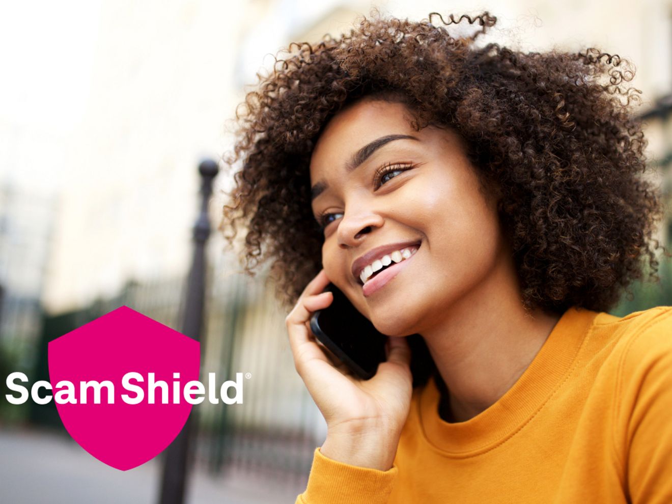 Una mano sosteniendo un teléfono que muestra la función de llamadas bloqueadas en la pantalla junto al logotipo de ScamShield.