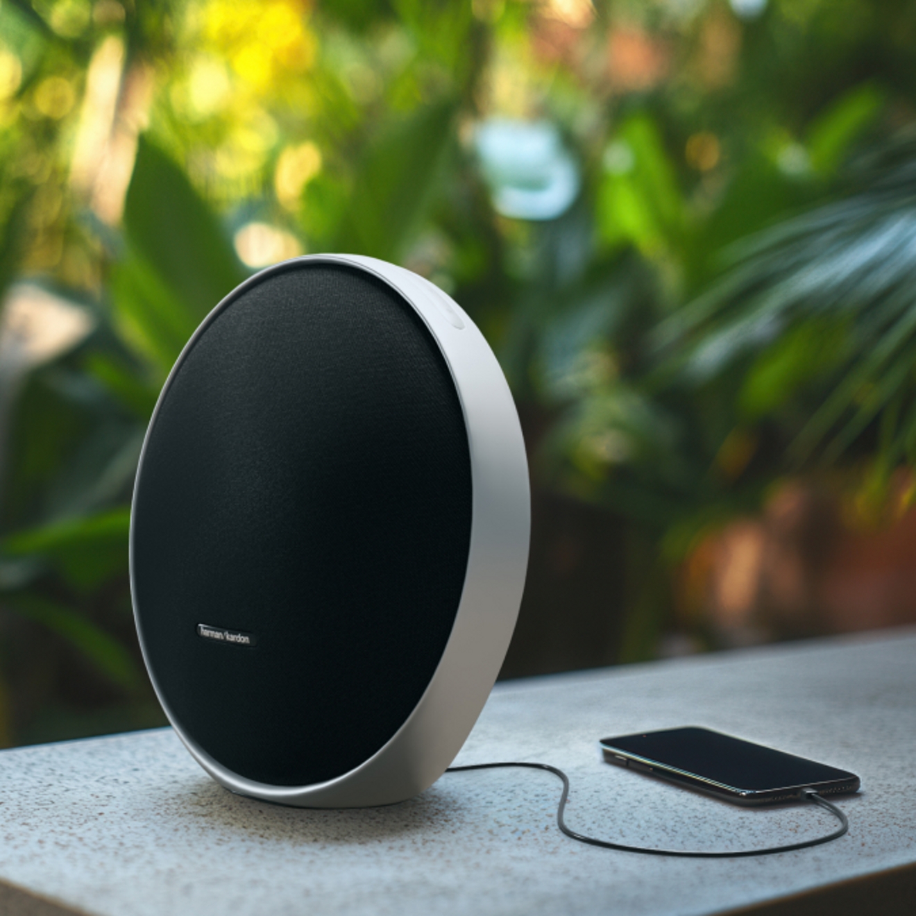 Imagen en primer plano de un teléfono conectado a una bocina Onyx Studio 9 al aire libre.