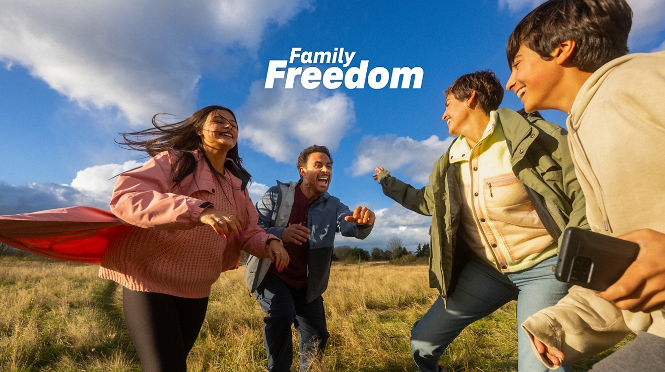 Una familia reunida alrededor de un camping junto al mar mirando un teléfono.