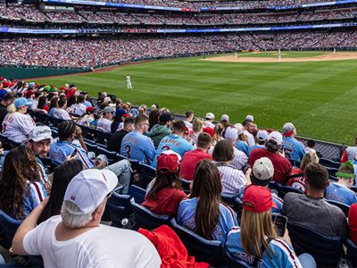 Una multitud sentada, viendo un partido en un estadio de béisbol.