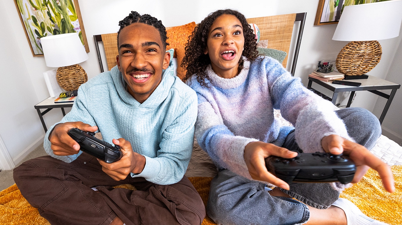 Dos personas sentadas en una cama jugando a un videojuego