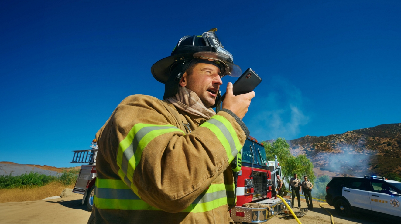 Un bombero en la escena de un incendio en una región remota usa un smartphone para proporcionar una actualización de estado.