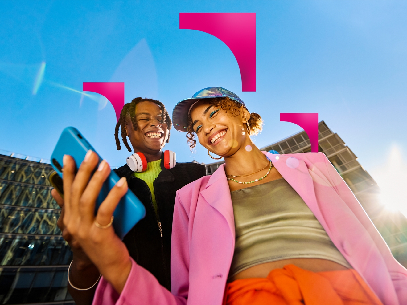 Dos personas sonrientes con sus smartphones en la mano al aire libre en un día soleado.