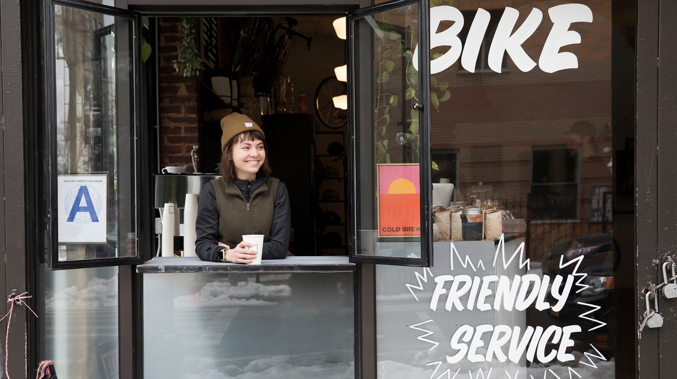 Una mujer bebiendo una taza de café en una ventana abierta.