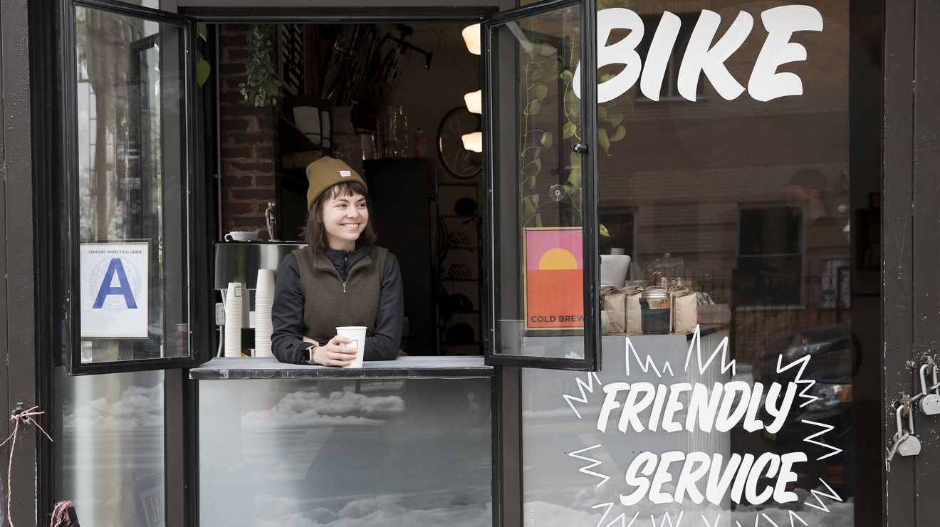 Una mujer bebiendo una taza de café en una ventana abierta.