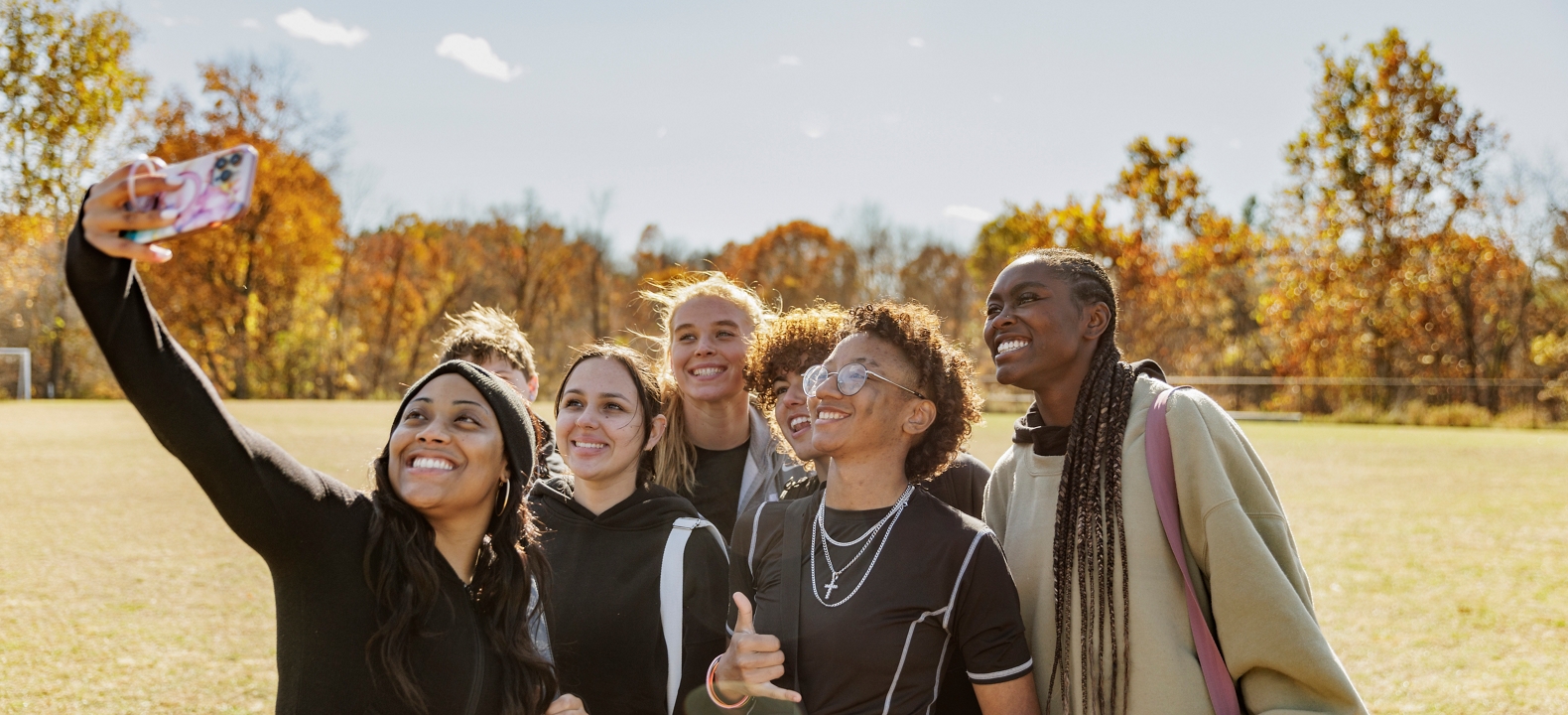 Grupo de amigos en un campo tomándose un selfie.