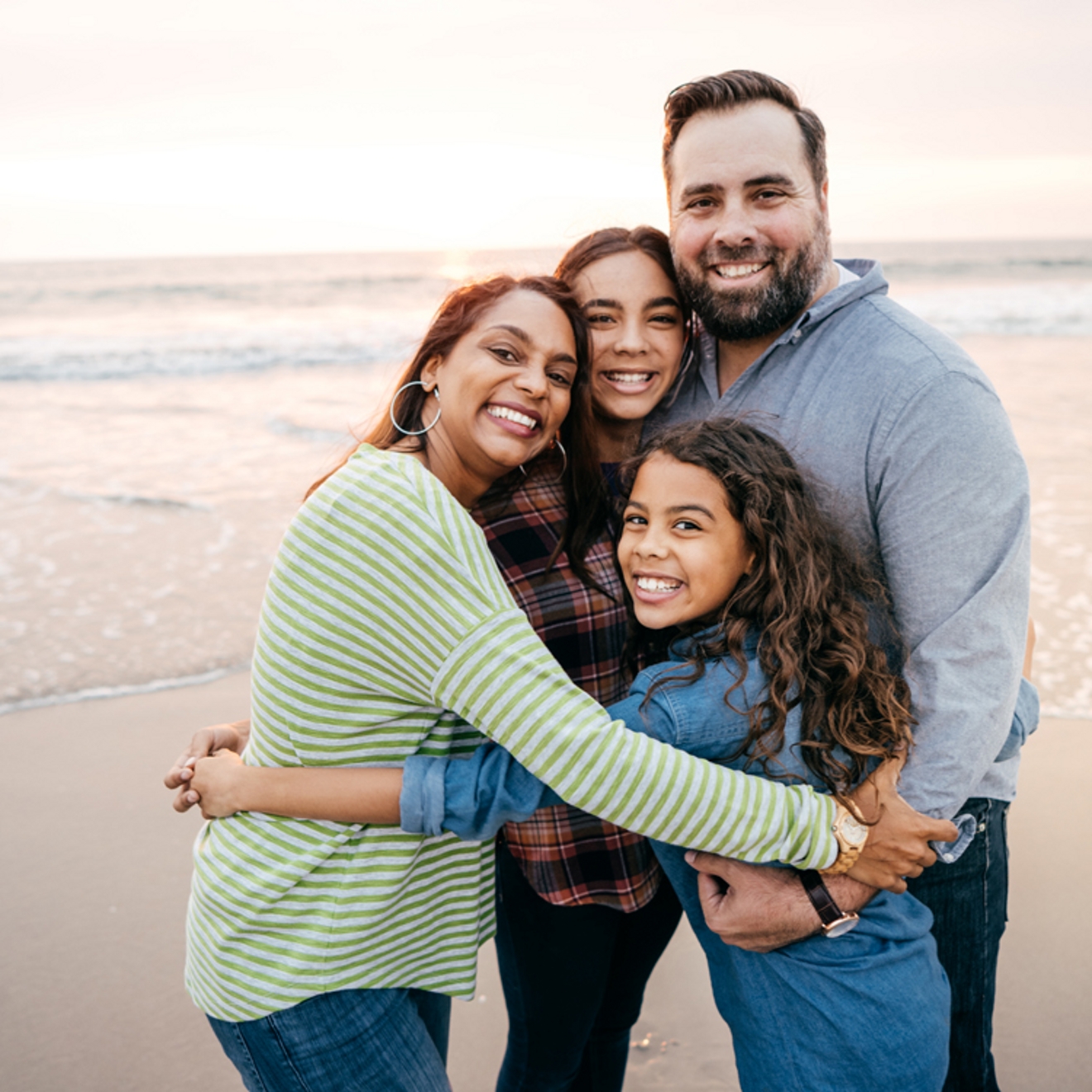 Familia de cuatro posando para una foto en la playa.