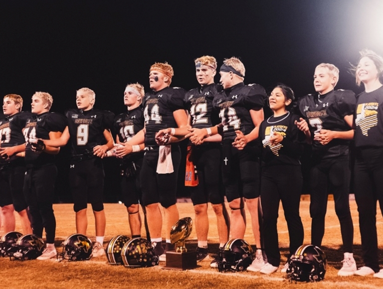 Miembros del equipo de fútbol de Happy High School están parados formando una línea sobre los laterales.