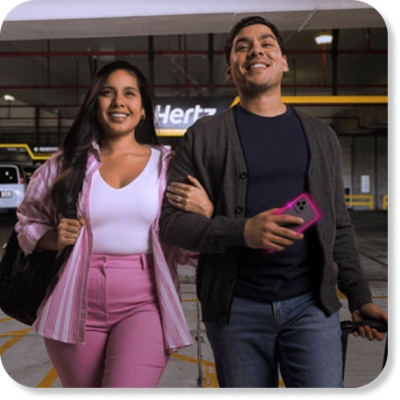 Una pareja joven camina por el estacionamiento de Hertz.