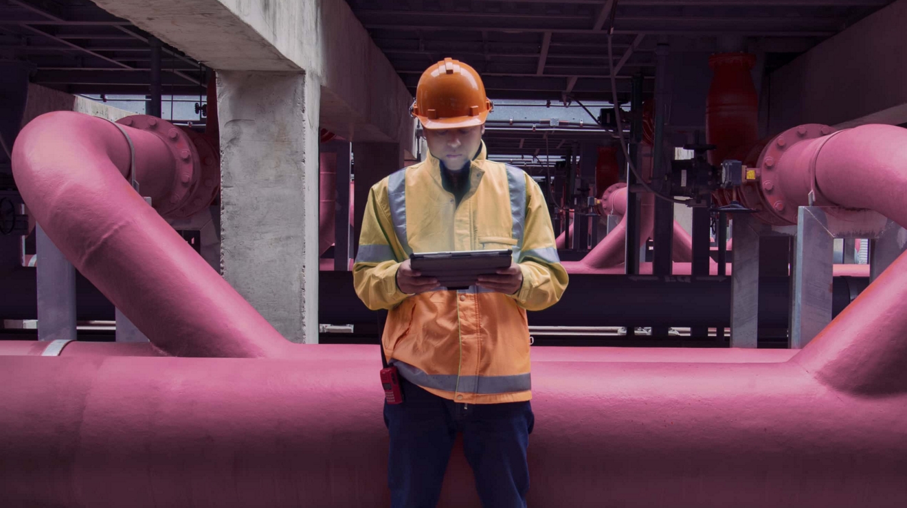 Un trabajador de una planta de tratamiento de agua supervisa los datos del sensor de nivel de presión y caudal en una tablet 5G.