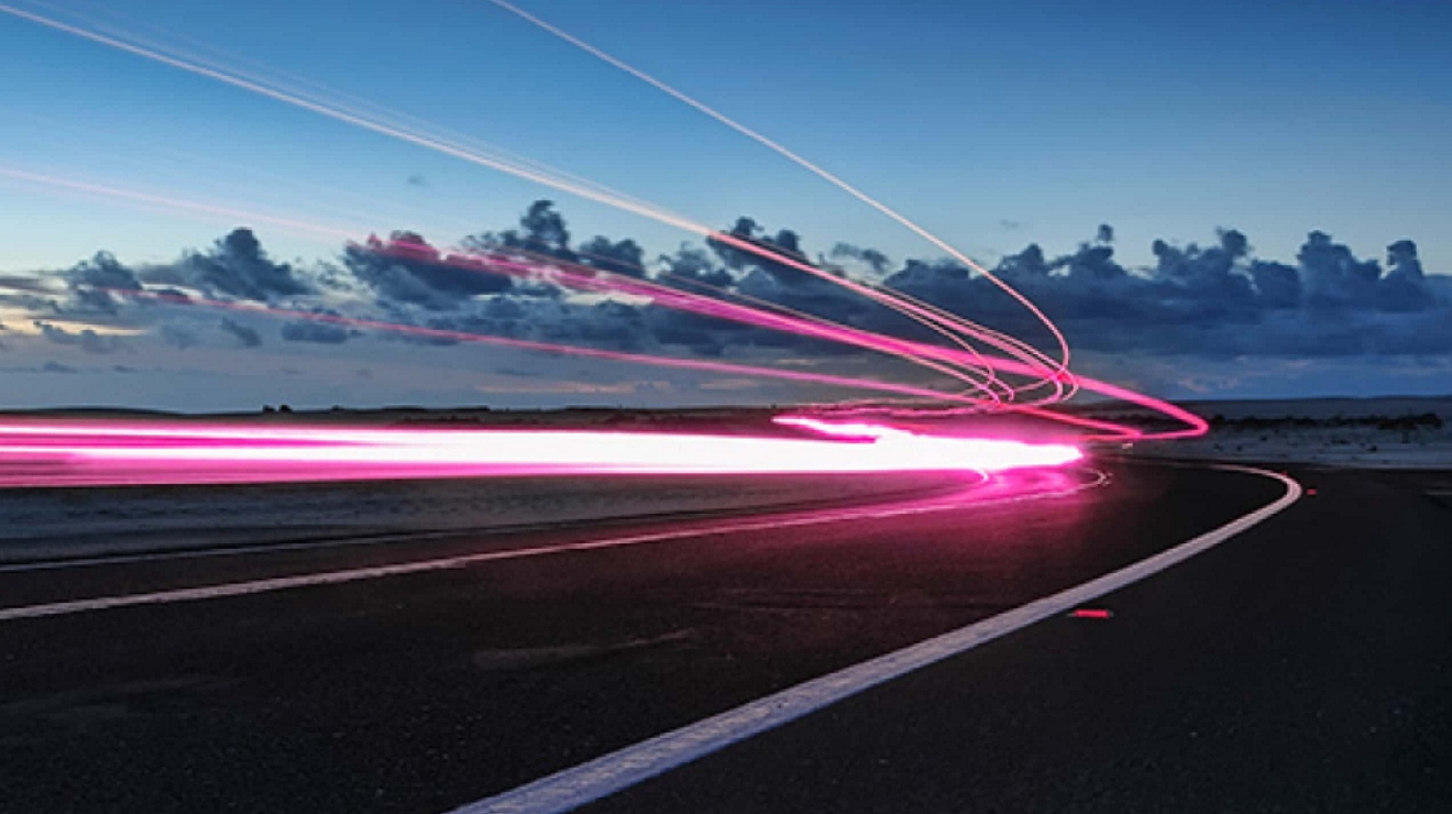 Dinámicos rastros de luz magenta brillan contra el cielo, para simbolizar la velocidad y conectividad de la red 5.