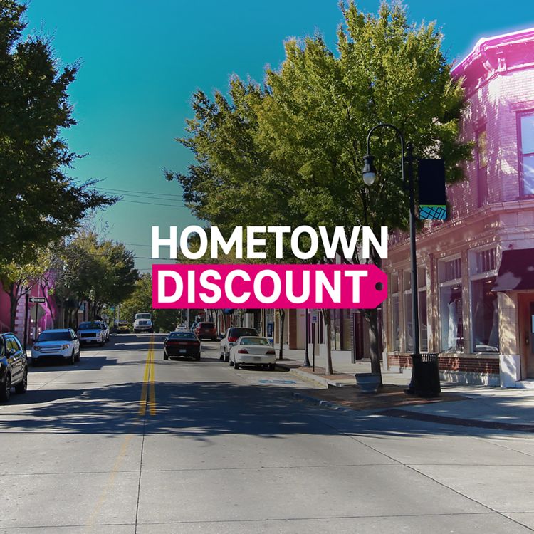 La calle principal de un pequeño pueblo con algunos edificios resaltados en magenta con el logotipo de Hometown Discount superpuesto