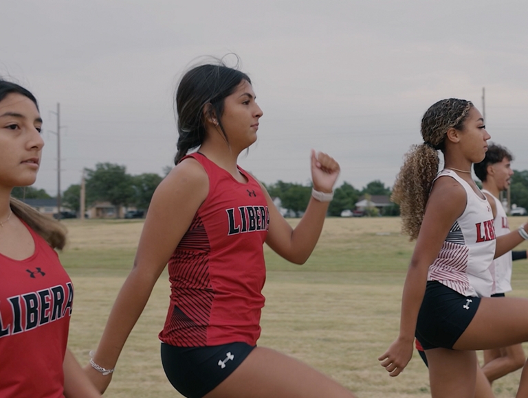 Atletas de Liberal High School, vestidos con uniformes negros y rojos, entran en calor antes de un evento.