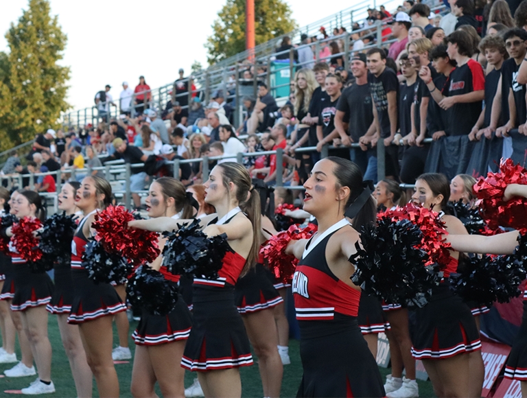 Animadoras de Loveland High School, vestidas con uniformes rojos y negros, animan a su equipo durante un partido.