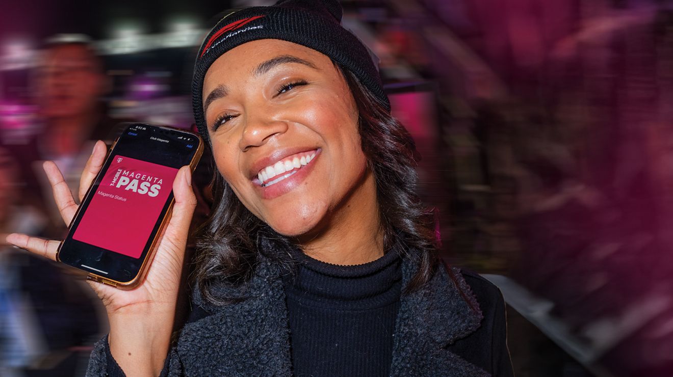 Una miembro de T-Mobile sonríe y muestra su Magenta Pass en un evento.