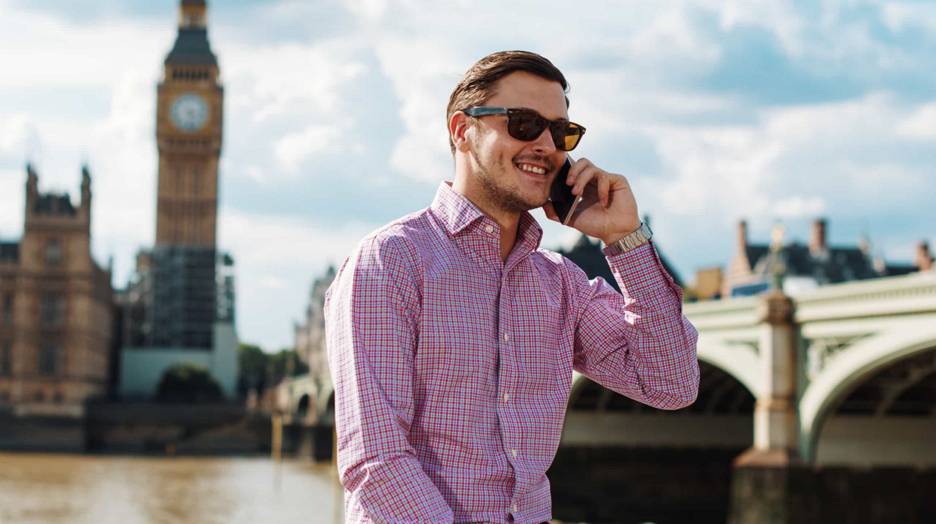 Una persona que viaja por negocios en Londres hace una pausa frente al Big Ben para conversar con colegas por teléfono.