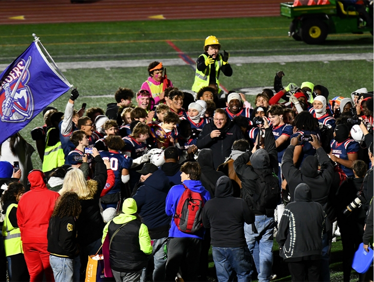 Un grupo de futbolistas de Manchester y otros estudiantes se reúnen en el campo después de un partido.