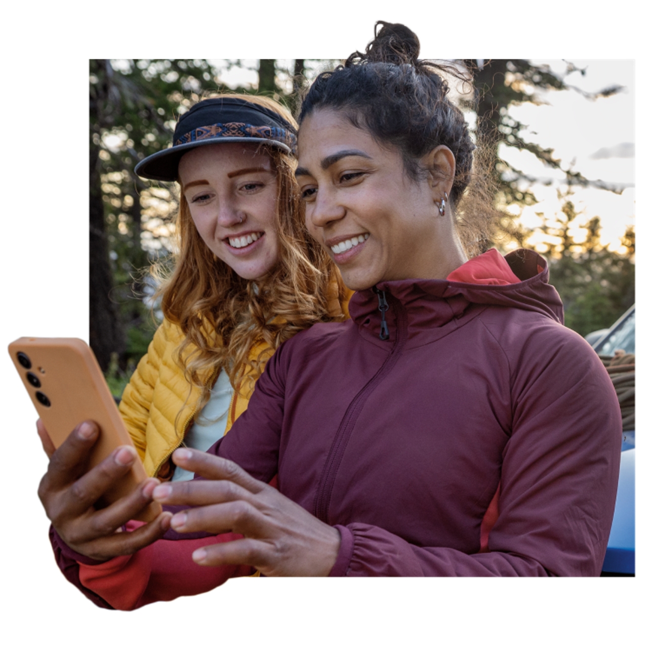 Una mujer envuelta en una manta a rayas sostiene su teléfono mientras sonríe para tomarse un selfie con un hombre.