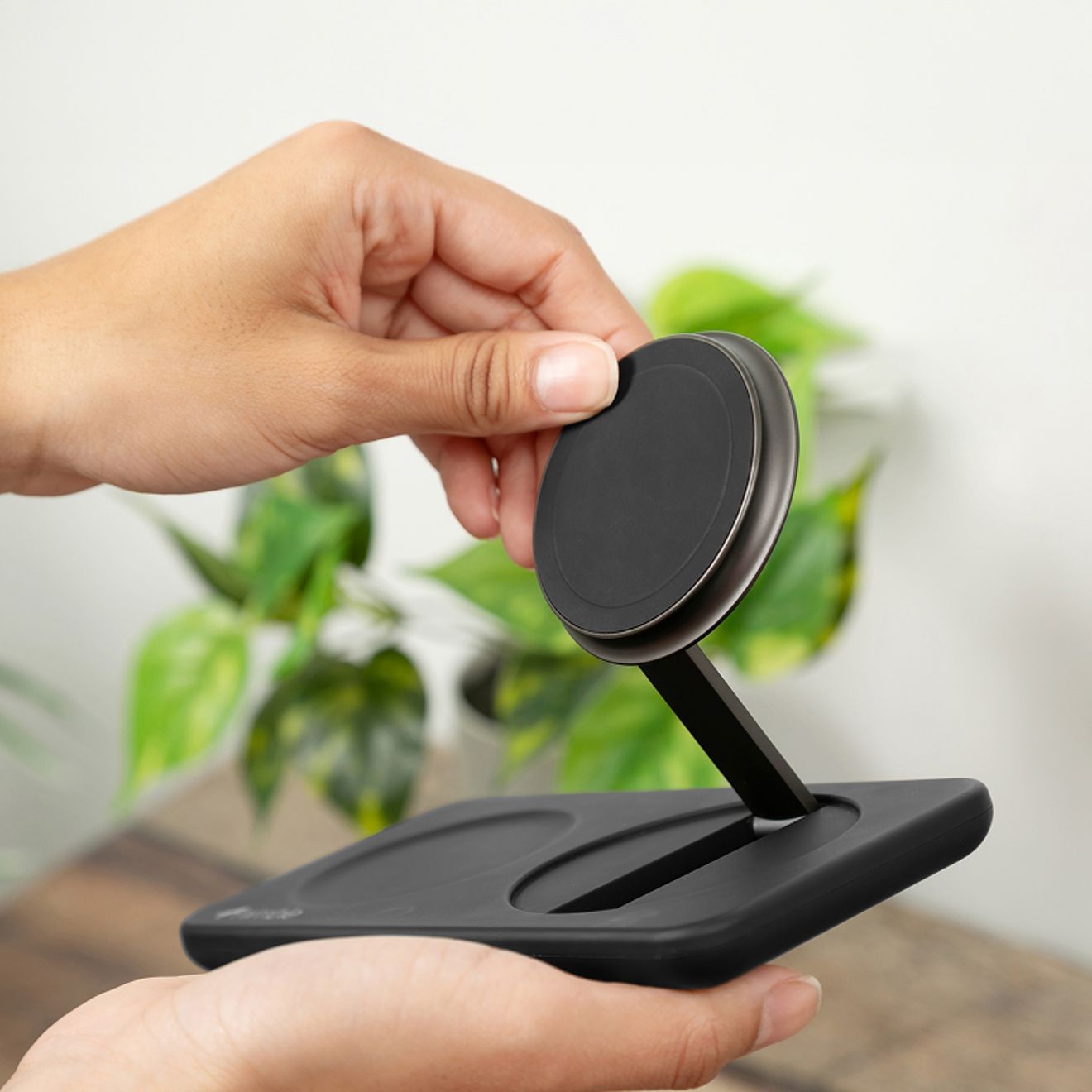 Una estación de carga inalámbrica 2 en 1 Nimble Fold de color negro descansa en la mano de una persona, con zonas de carga dedicadas para un smartphone y audífonos inalámbricos.