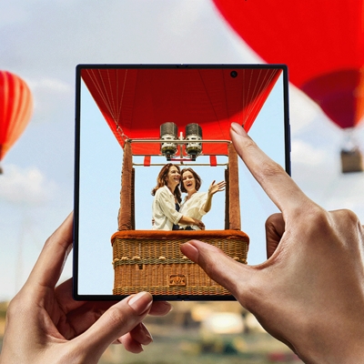 Imagen de alguien tomando una foto de dos amigos que están subiendo a un globo aerostático con un Galaxy Z Fold7.