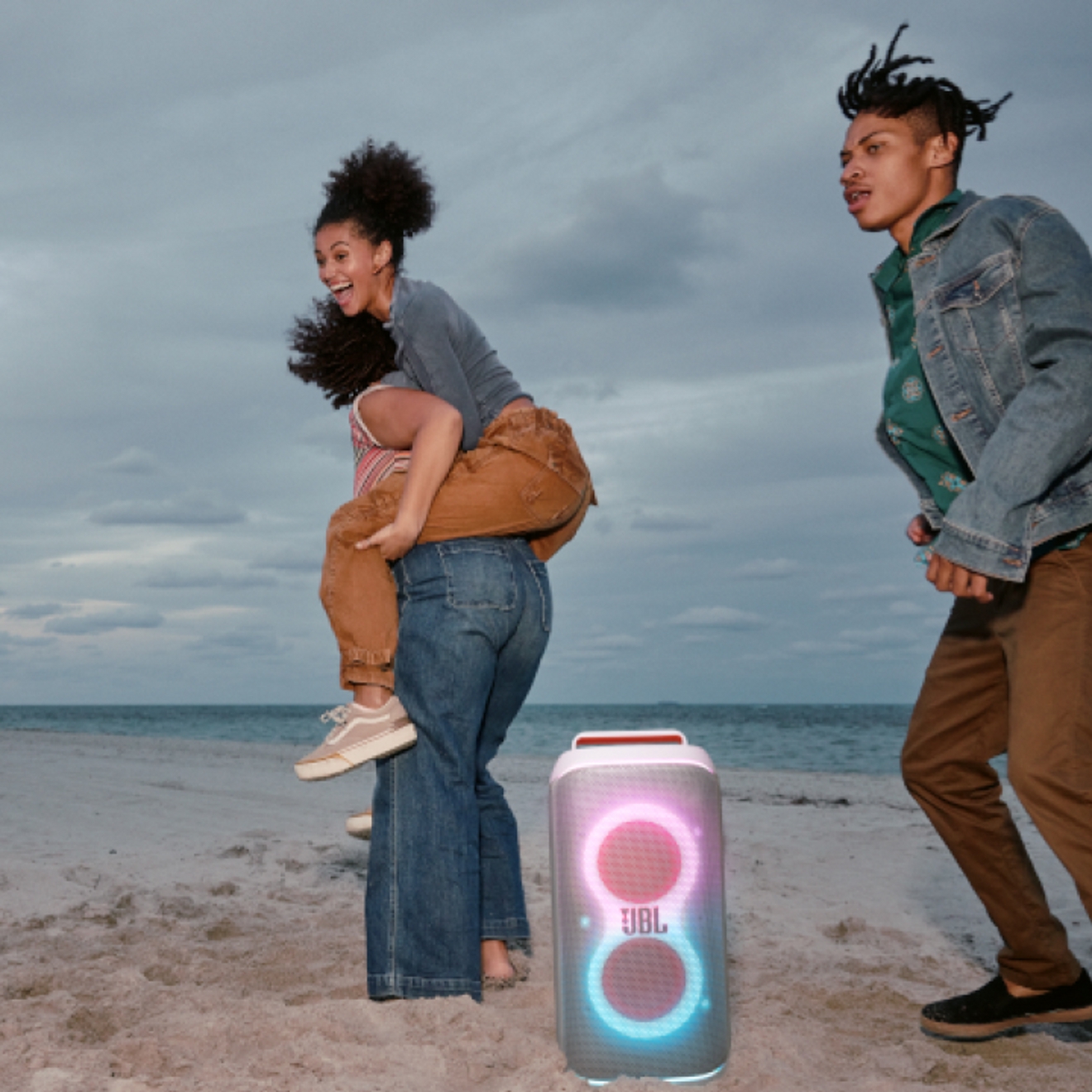 Tres amigos en la playa disfrutando con una JBL PartyBox Club 120