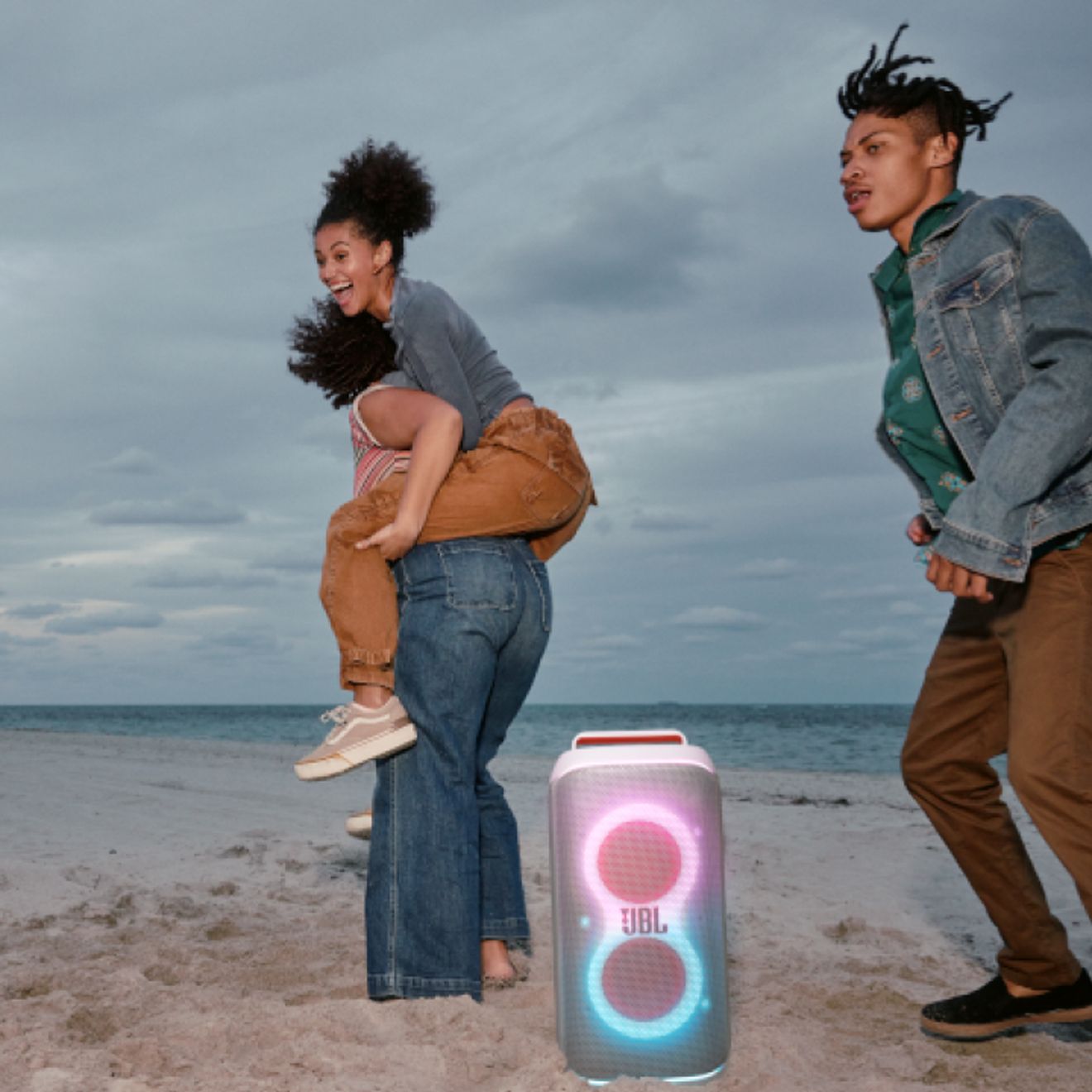 Tres amigos en la playa disfrutando con una JBL PartyBox Club 120