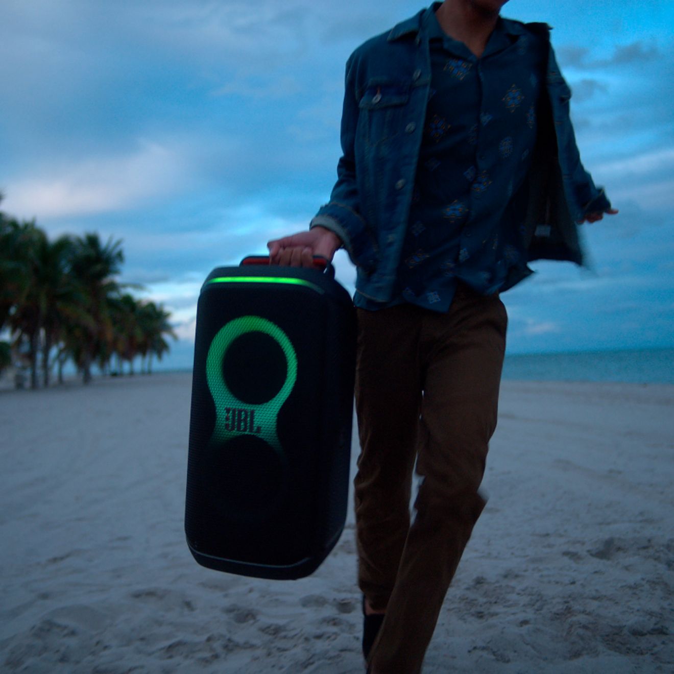 Una persona llevando una JBL PartyBox Club 120 por su asa plegable.