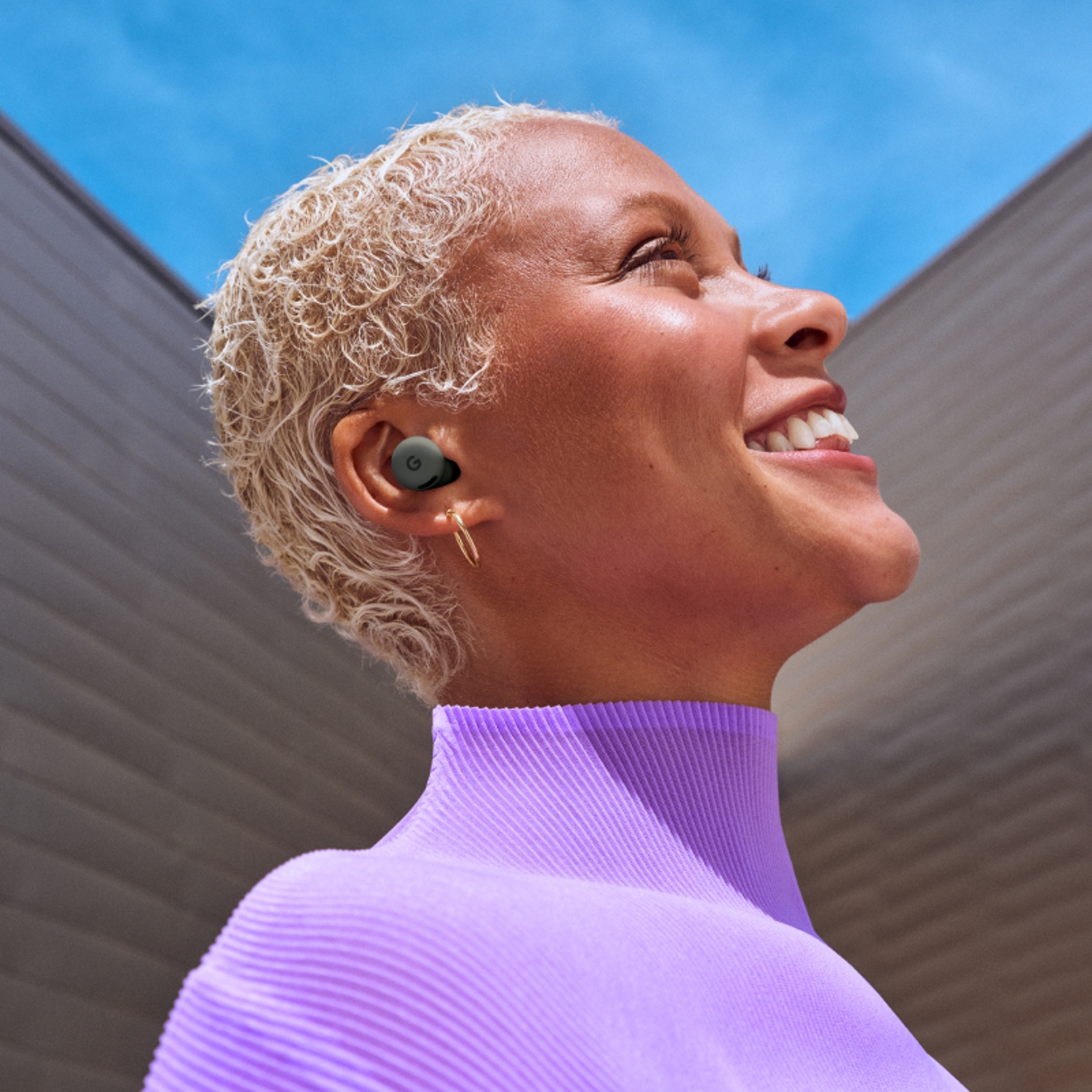 Una mujer sonriendo mientras usa el Google Pixel Buds 2a