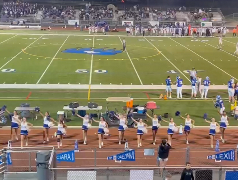 Vista aérea del campo de fútbol de Pleasant Valley, con los jugadores en el campo y las animadoras en los laterales.