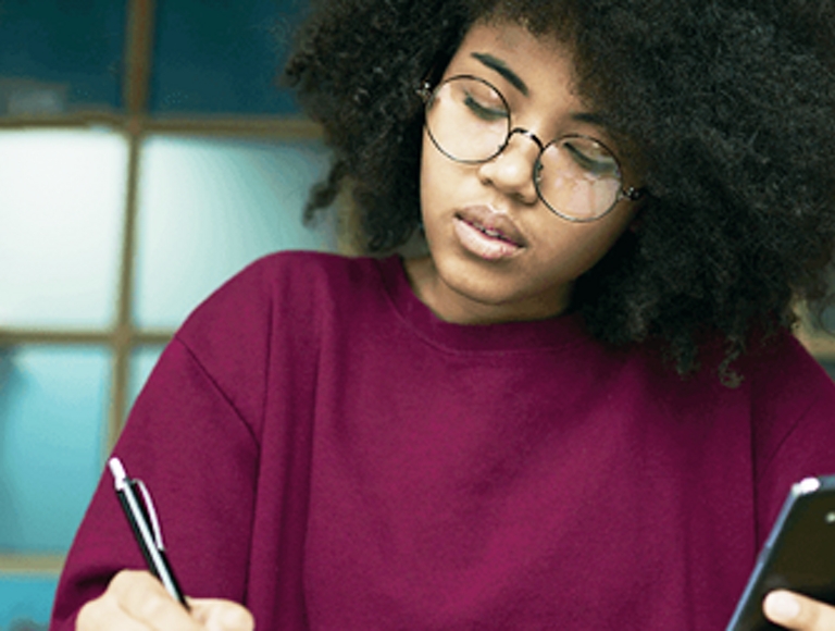 Mujer estudiando y sosteniendo un teléfono