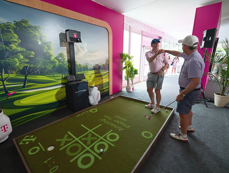 Dos aficionados al golf chocan los puños mientras utilizan un simulador de golf.