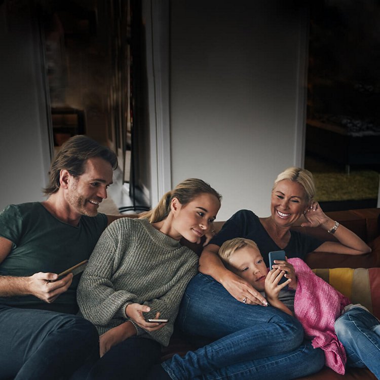 Familia en el sofá mirando sus dispositivos móviles