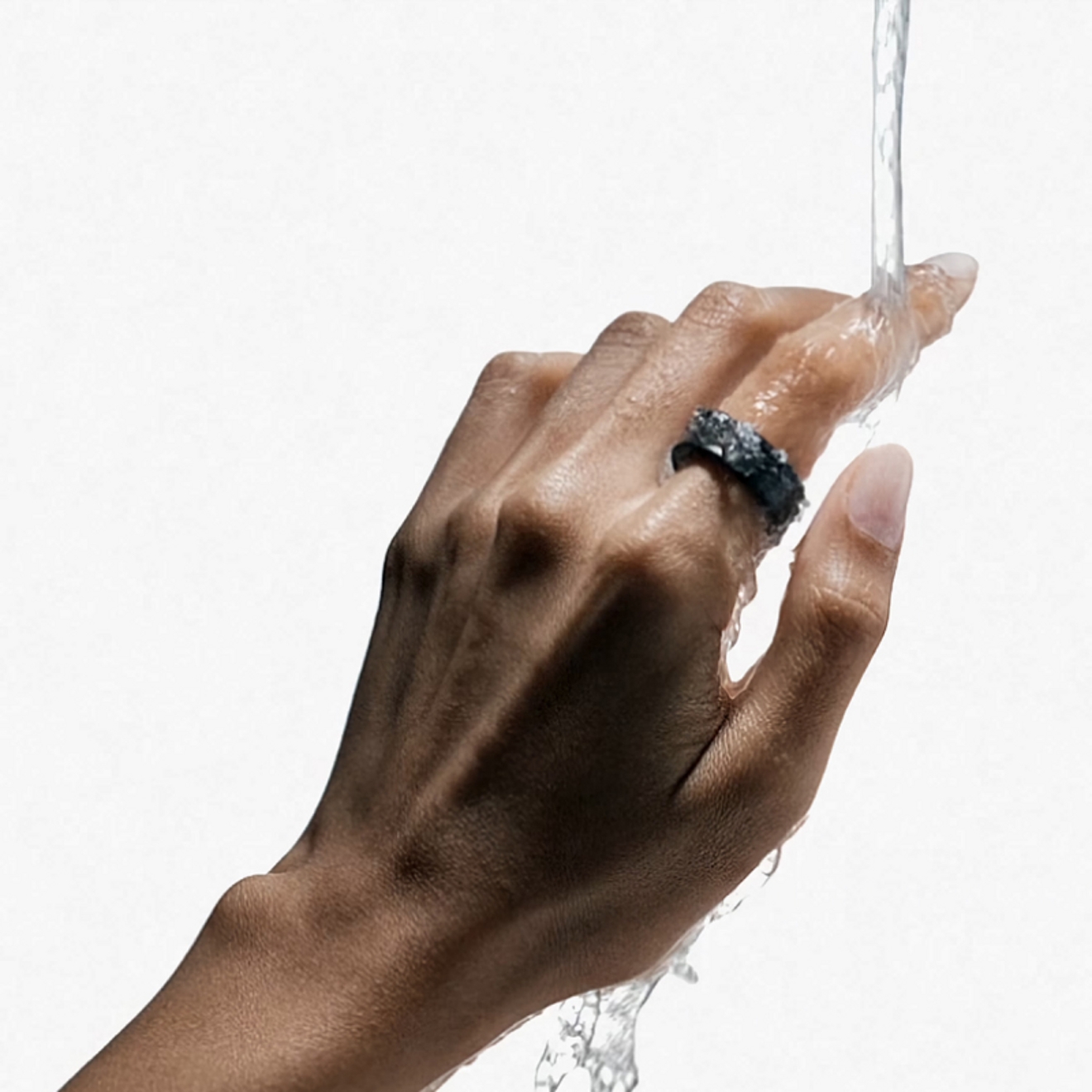 Una mano con un Galaxy Ring bajo un chorro de agua.