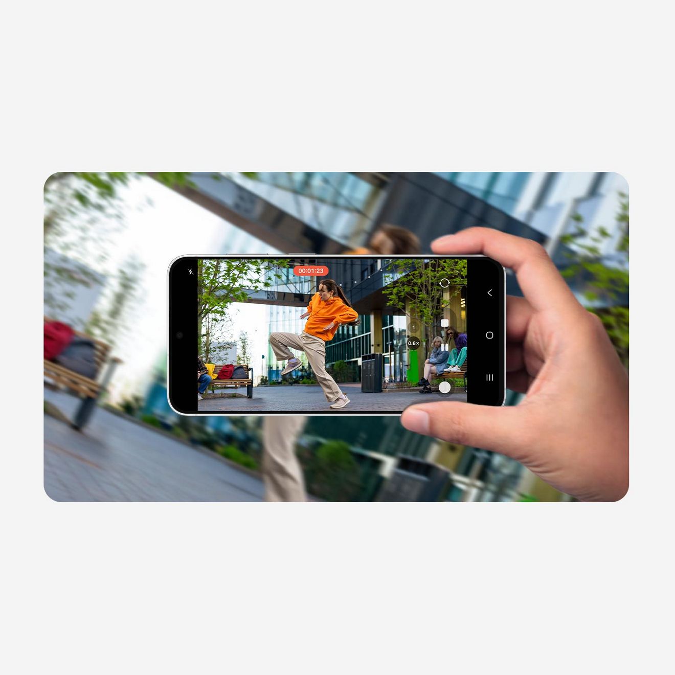 A hand holds the Samsung Galaxy S26 FE. The phone is displaying a freeze-frame of a skateboarder performing a trick on a city sidewalk.