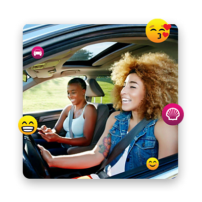 Dos chicas conduciendo mientras se ríen, rodeadas de emojis.