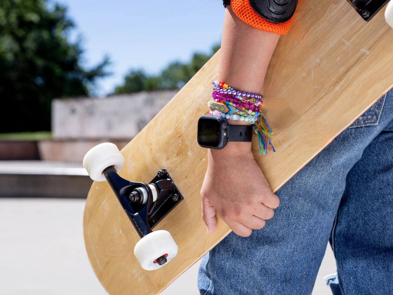 Reloj SyncUP KIDS en un brazo que sostiene una patineta.