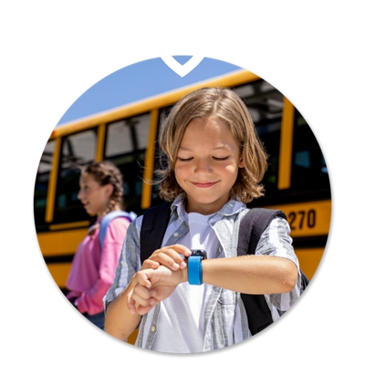 Un niño mirando el reloj SyncUP KIDS delante de un autobús escolar.