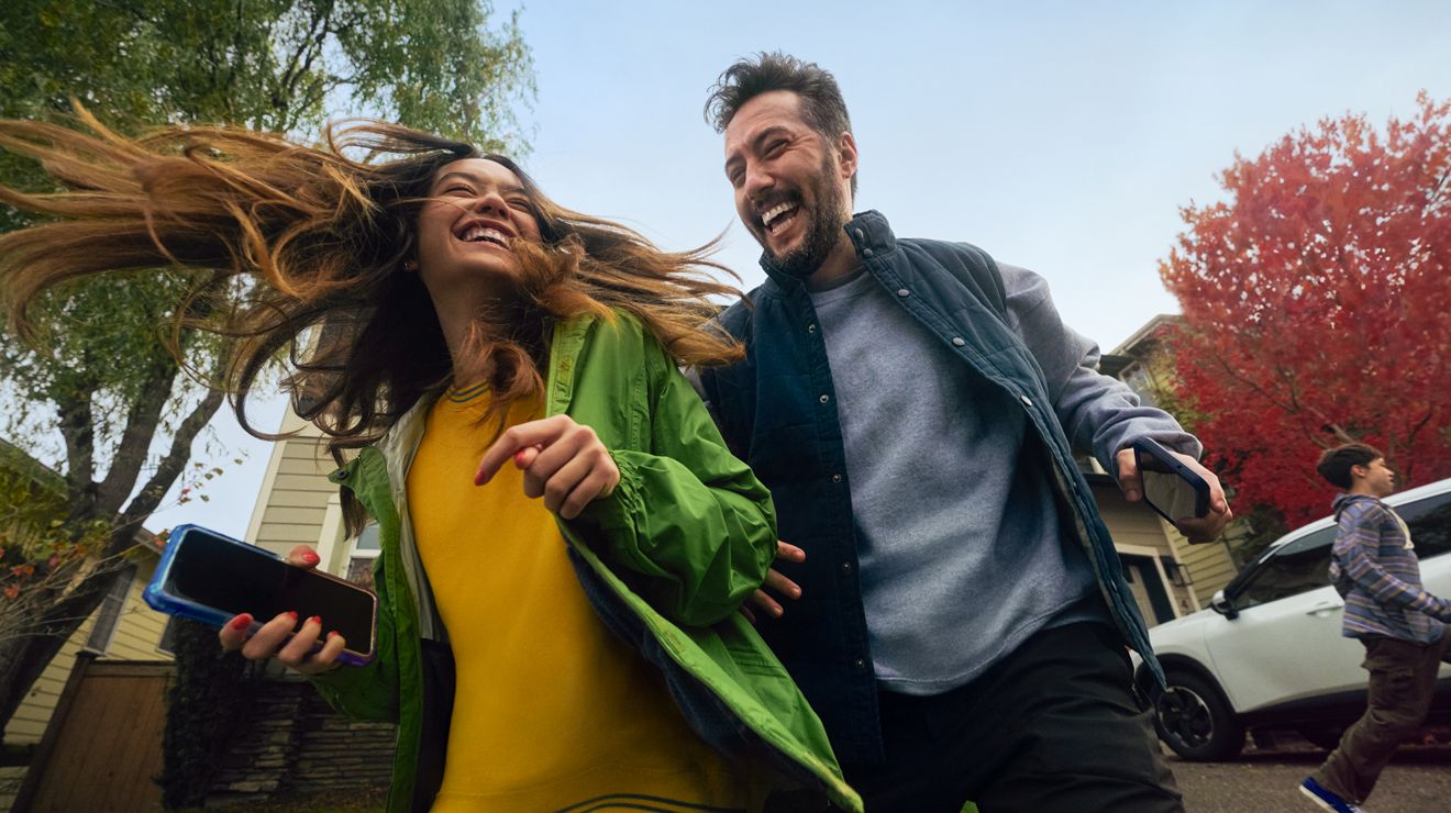 Pareja riendo en el otoño mientras un niño corre en el fondo.