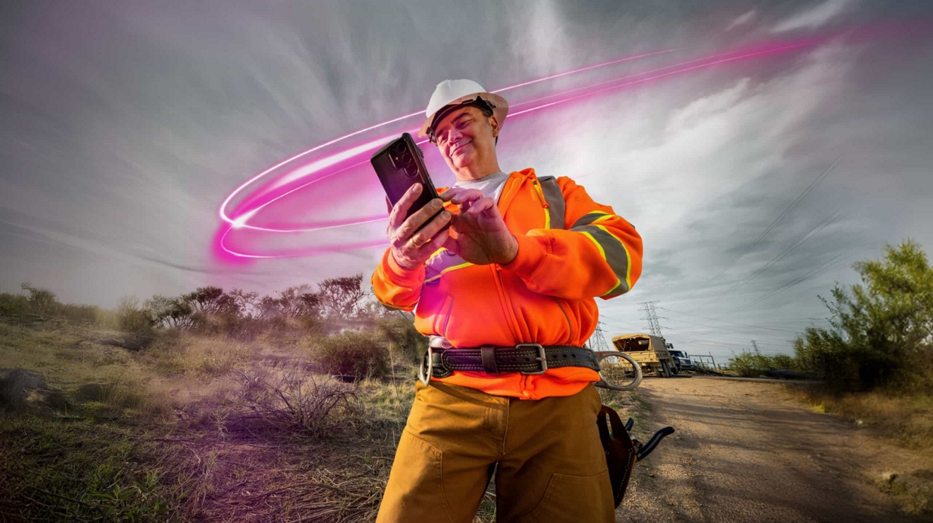 Un especialista en servicios públicos trabajando sobre el terreno utiliza T-Satellite con Starlink para consultar los mensajes de su teléfono móvil.