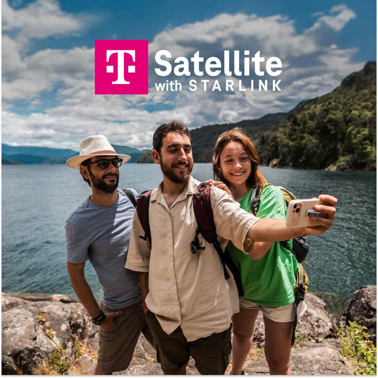 Un grupo de amigos se saca un selfie en la costa rocosa de un lago con montañas en el fondo y el texto "T Satellite con Starlink".