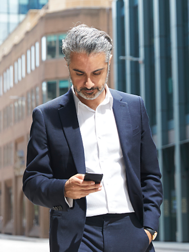Un profesional de los servicios financieros utiliza su smartphone mientras camina por la calle.