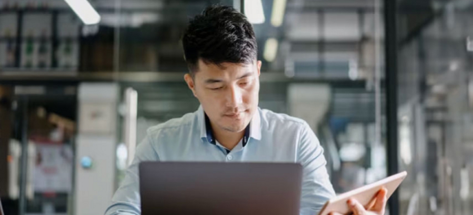 Joven profesional utiliza una laptop y una tablet al mismo tiempo.